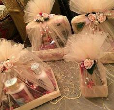 three small boxes with pink flowers and tulle on top of a lace doily