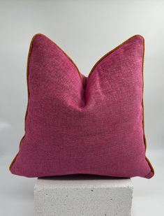 a pink pillow sitting on top of a white block