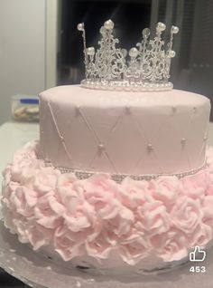 a three tiered cake with pink flowers and a tiara on top is shown