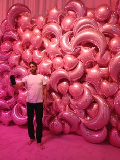 a man standing in front of pink balloons