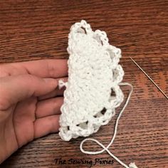 someone is crocheting the end of a piece of white yarn on top of a wooden table