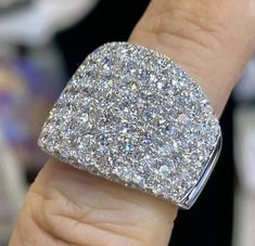 a close up of a person's hand with a diamond ring on their finger