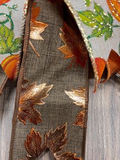 an orange and gold leaf print ribbon on a wooden surface with sequins in the background