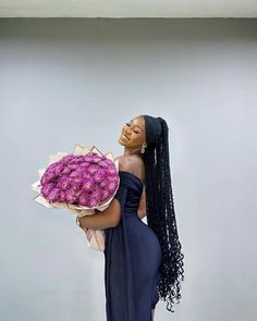 a woman holding a large bouquet of pink flowers