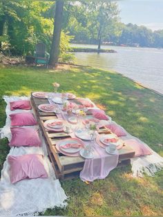 a picnic table set up with plates and pink napkins