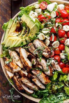 a salad with chicken, tomatoes, avocado and lettuce on it