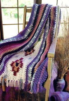 a crocheted blanket sitting on top of a wooden chair