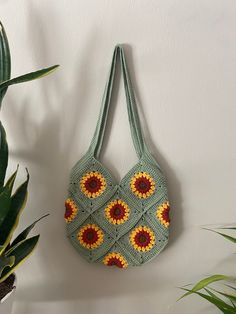 a crocheted bag hanging on the wall next to a potted plant and houseplant