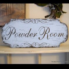 a wooden sign sitting on top of a shelf next to a potted plant and framed pictures