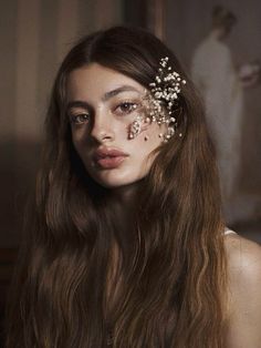 a woman with long brown hair and flowers in her hair is wearing a head piece