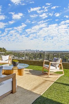 an outdoor patio with chairs and tables overlooking the cityscape on a sunny day