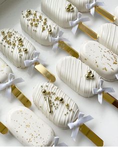 some white and gold decorated desserts are arranged on a table with ribbons around them