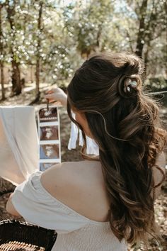 a woman standing in the woods with her hair styled into a half - up braid