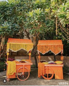 an orange and yellow cart sitting next to each other in front of a lush green tree