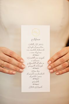 the bride is holding her wedding program in her hands with gold rings on their fingers