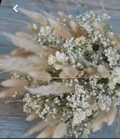 a bouquet of dried flowers sitting on top of a wooden table next to a blue wall