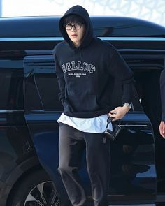 a young man in black hoodie and sweatpants stepping out of a car with his hand on his hip