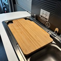 a wooden cutting board sitting on top of a sink