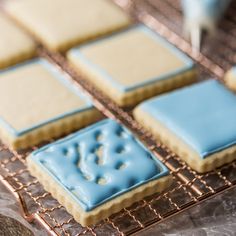 some cookies are sitting on a cooling rack and one is frosted with blue icing