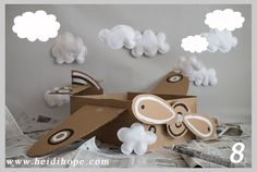 an airplane made out of cardboard sitting on top of newspaper paper with clouds above it