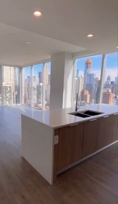 an empty kitchen and living room in a high rise building with floor to ceiling windows