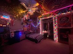 a bedroom decorated with christmas lights and decorations on the ceiling is lit by colorful lights