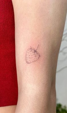 a small strawberry tattoo on the arm