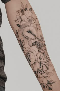 a person with a tattoo on their arm has flowers and an owl in the middle