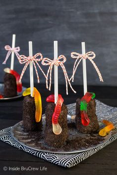 chocolate cake pops decorated with gummy worms and candy canes on a plate, ready to be eaten