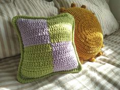 two crocheted pillows sitting on top of a bed next to eachother