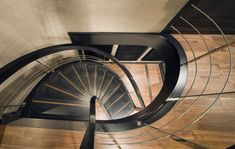 a spiral staircase is shown from the top down to the floor below it, with wood floors and metal railings