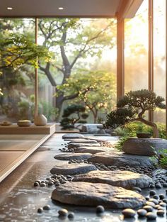 a garden with rocks and plants in the center, near large windows that look out onto trees