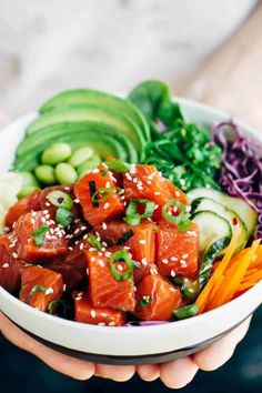 a person holding a bowl filled with meat and veggies on top of it