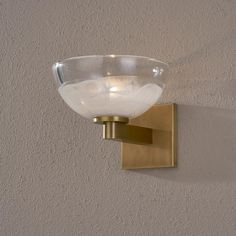 a glass bowl mounted on the wall next to a light fixture with a gold finish