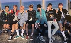 group of young men sitting next to each other on a window sill near the ocean