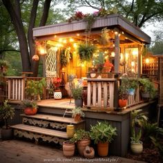 an outdoor deck with potted plants and string lights on the porch, next to a tree