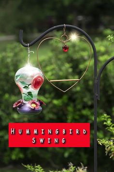 a hummingbird feeder hanging from a metal pole with the words hummingbird swing on it