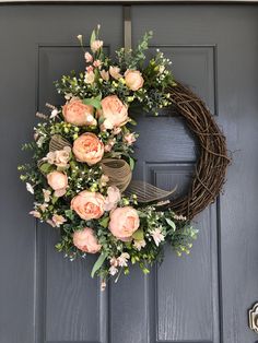 a wreath with pink flowers hanging on the front door