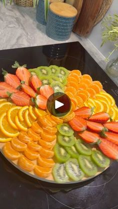 a platter filled with sliced fruits and vegetables on top of a black countertop