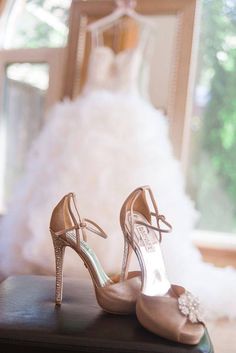 a pair of high heeled shoes sitting on top of a table next to a wedding dress