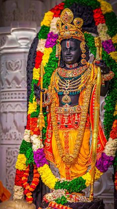 a statue of the hindu god in front of flowers