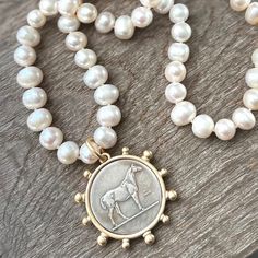 Great gift idea for the horse lover in your life! This beautiful necklace design features hand knotted white freshwater pearls and a reproduction horse coin pendant. Necklace is 18 inches in length and coin pendant is 40mm round. Pearls are approximately 9-10 mm in size.  Pendant bezel is matte gold. Pearls are authentic freshwater potato pearls. Clasp is gold (brass). I also carry freshwater pearl stud earrings that coordinate nicely with this necklace. They can be found here: https://www.etsy.com/listing/1324859137/luxe-pearl-studs-freshwater-pearl-studs?click_key=d07efc4535abf278793858c89410802cceb6220e%3A1324859137&click_sum=6c40c58e&ref=shop_home_active_1&pro=1 Necklace is also available in a silver version with gray freshwater pearls. Message me for a photo! Horse Necklace, Coin Pendant Necklace, Necklace Design, Gifts For Horse Lovers, White Freshwater Pearl, Gold Brass, Coin Necklace, Coin Pendant, Pearl Stud Earrings