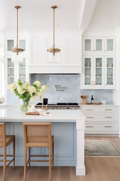 a kitchen with white cabinets and wooden chairs in front of the counter top, along with two bar stools