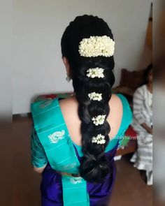 a woman with long black hair wearing a blue sari and flowers in her hair