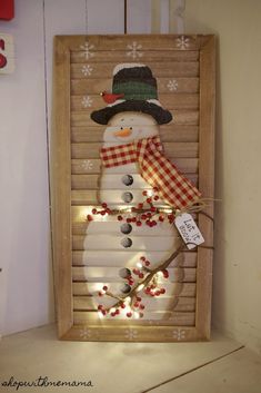 a snowman made out of shutters with lights on it and a tag hanging from the side