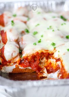 a casserole dish with meat and cheese covered in sauce, garnished with parsley