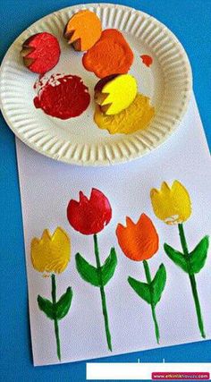 a paper plate with flowers and leaves on it next to a white paper plate that has red, yellow, and orange flowers