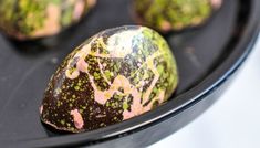 some kind of chocolate covered with green and pink sprinkles on a black plate