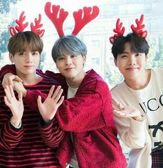 three young men standing next to each other with reindeer antlers on their heads and hands