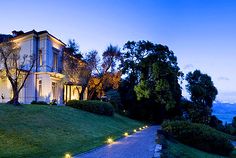 a large white house sitting on top of a lush green hillside